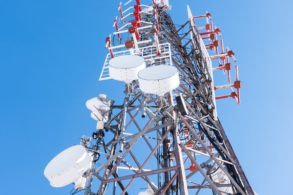 A telecommunication tower with many antennas against a clear blue sky.