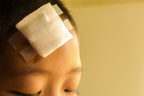 A young Asian child with a bandage on his forehead. 