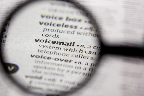 Illustration showing a magnifying glass focusing on the word voicemail in the dictionary.  