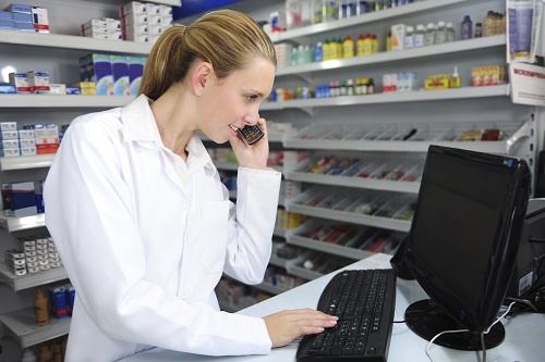 Pharmacist using the phone as she checks her computer monitor. 