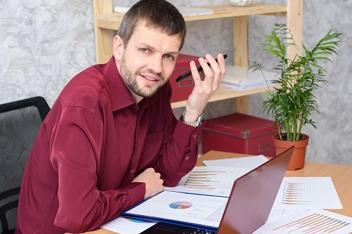Man in an office listing to a voicemail message on his mobile phone. 