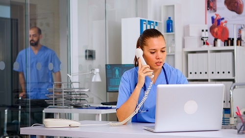 Medical staff at a nurses' station talking on the phone from a patient about their diagnosis. 