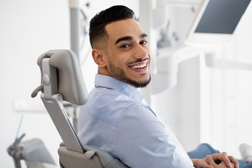 Dental clinic patient smiling as he sits in a dental chair. 