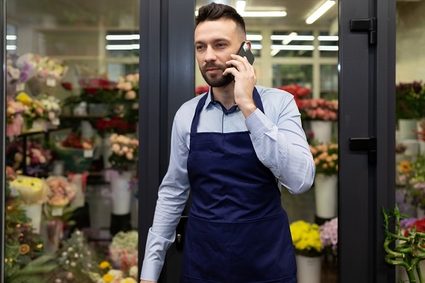 florist businessman talking on the phone next to the refrigerator with flowers