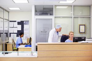 A doctor talking to his receptionist at the front desk with the help of IVR prompts for hospitals