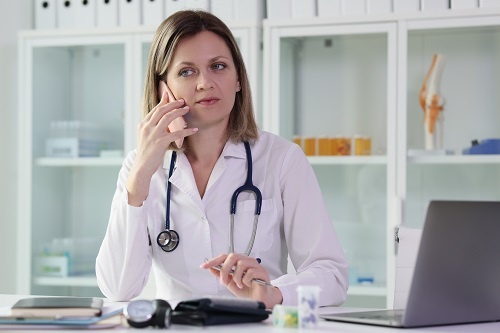 Therapist works in hospital and listens to her clients questions on phone.