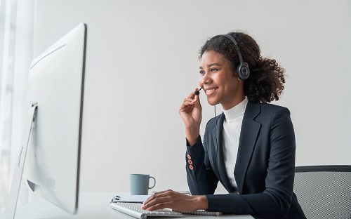 Close up call center operator in wireless headset talking in front of a computer. 